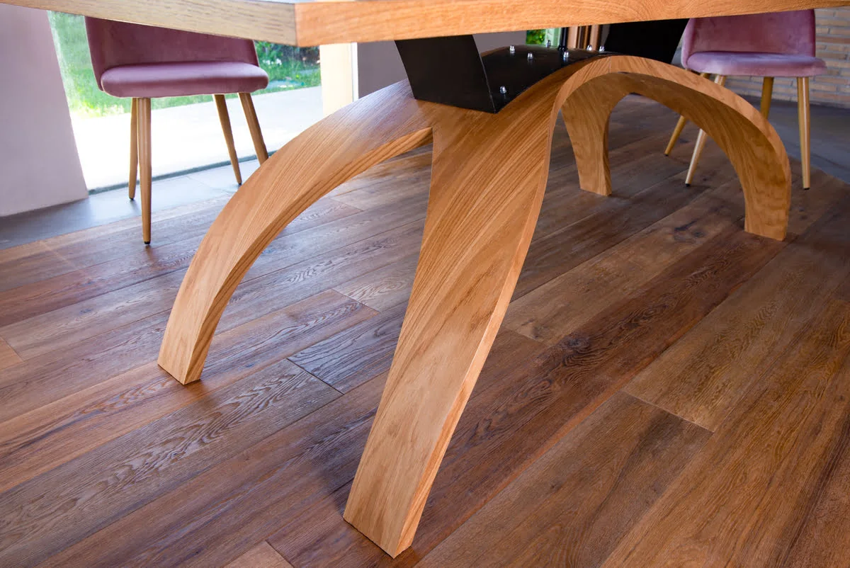 Dettaglio della base del tavolo "Old Bridge" Primo piano delle gambe ad arco in legno del tavolo "Old Bridge", evidenziando la qualità artigianale e il design curvilineo.