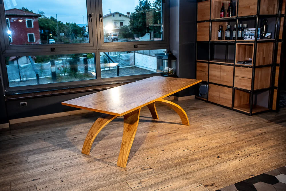 Dettaglio della base del tavolo "Old Bridge" Tavolo in legno con piano rettangolare e base elegante ad arco, perfetto per ambienti accoglienti e dallo stile contemporaneo.